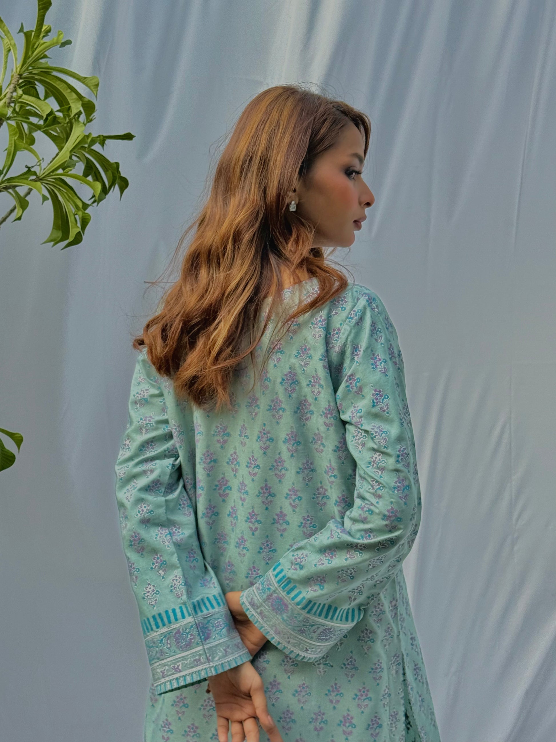 Woman wearing a light green floral dress against a plain background